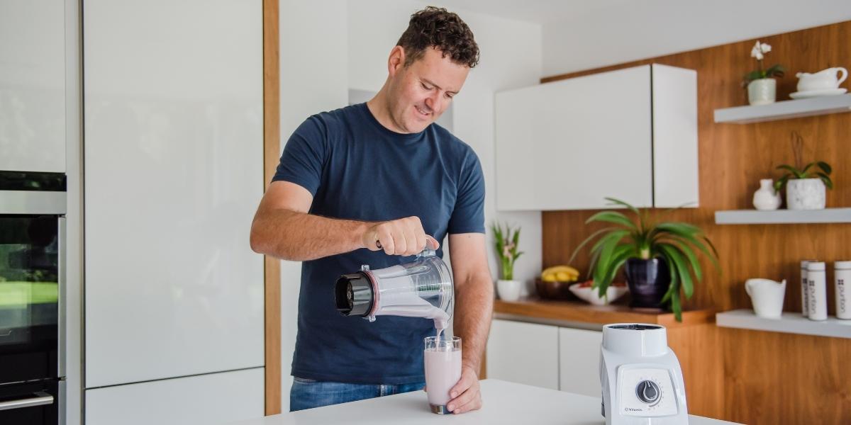 Edward Taylor pouring Purition Strawberry into a glass in his kitchen