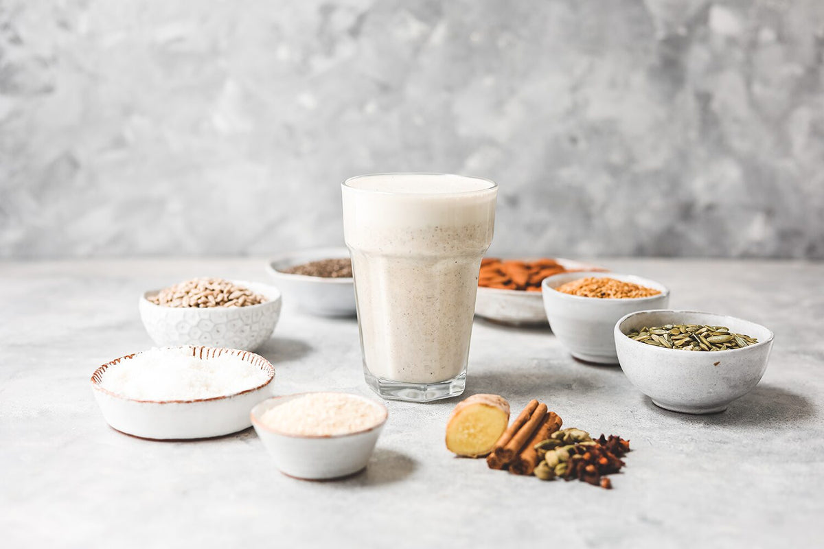 Glass of Purition Chai Latte surrounded by bowls of whole food ingredients