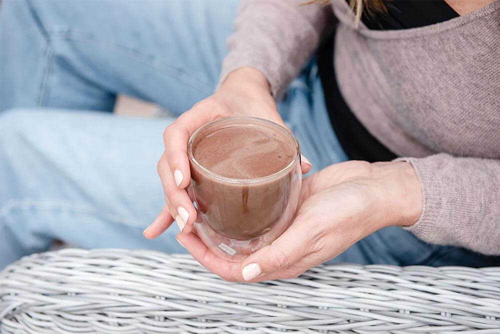 Person holding a mug of Purition's Hot Chocolate Super Latte