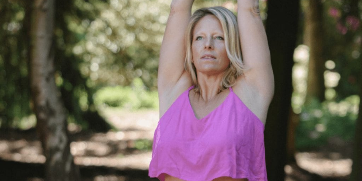 Yoga teacher Vicki Snow in forest with arms up