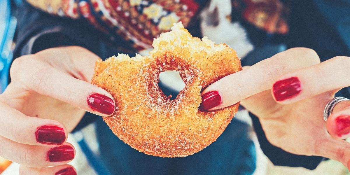 Photograph of a person holding a very sugary donut