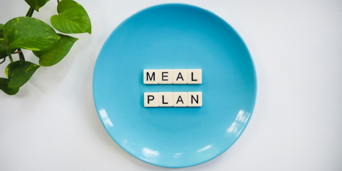 Bright blue circular plate with the wrods MEAL PLAN spelled out in scrabble letters.