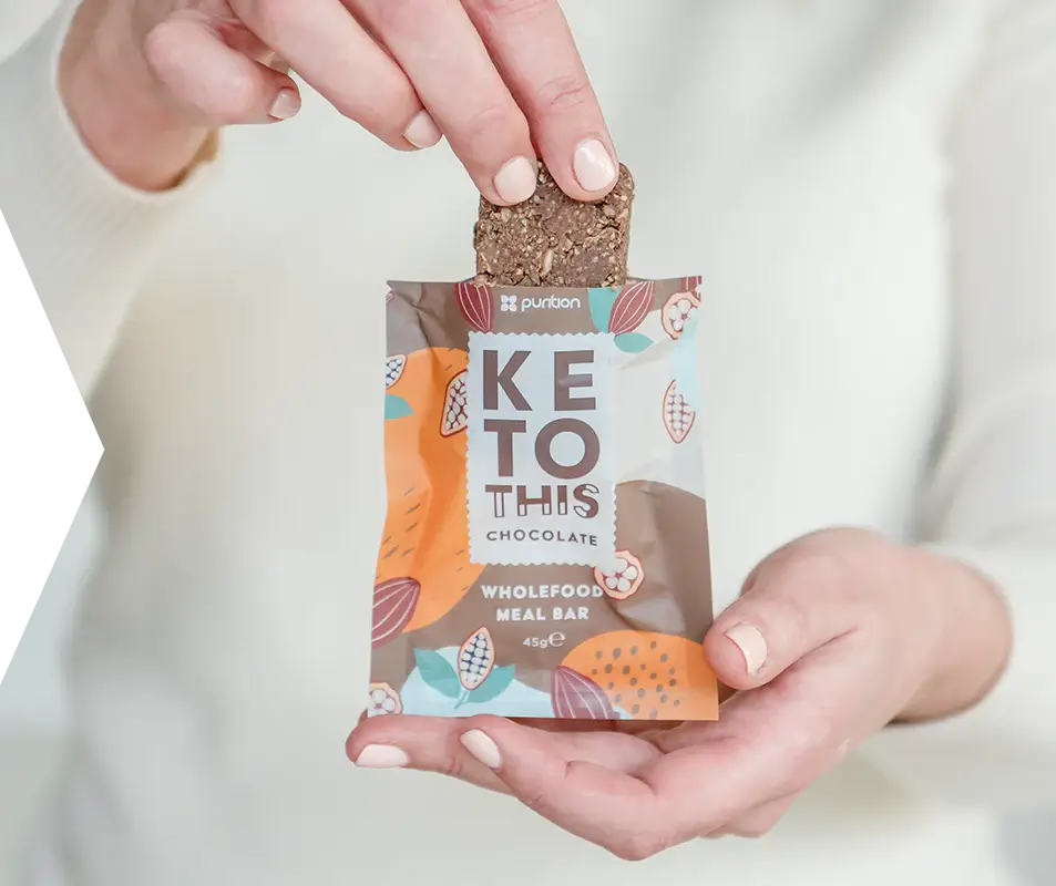 Person removing a Purition Chocolate wholefood meal bar from the fully recyclable paper packaging.