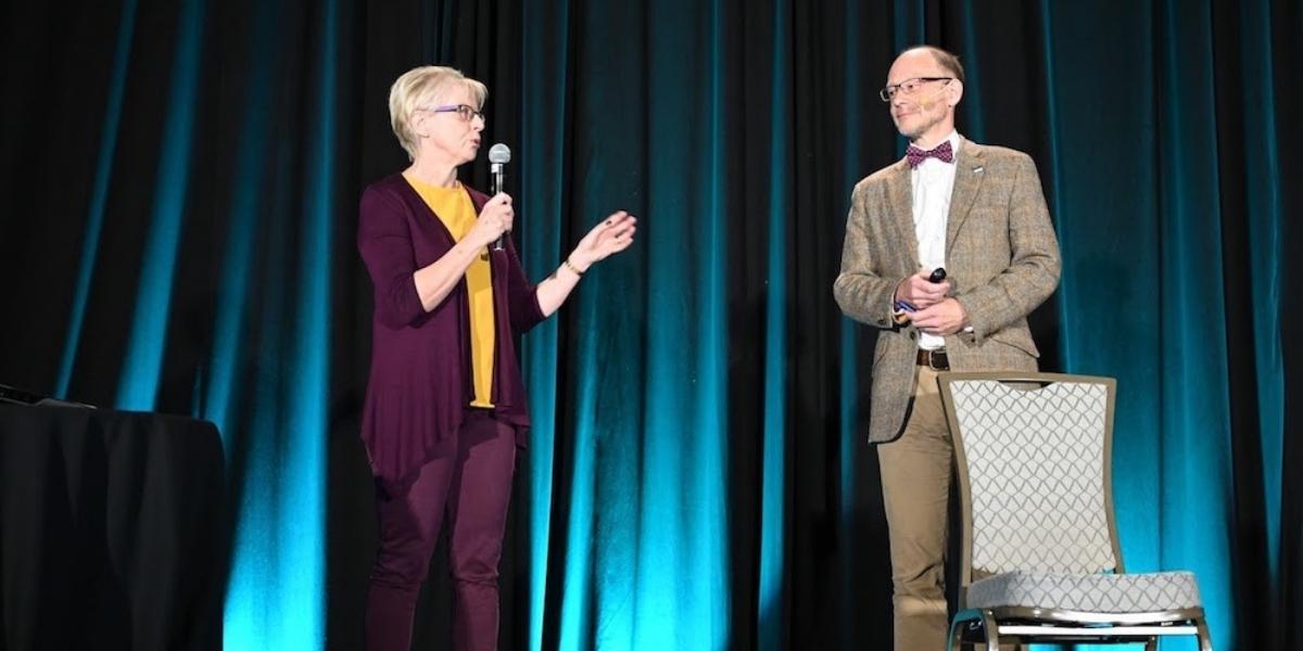 Photograph of husband and wife team Dr David Unwin and Dr Jen Unwin speaking on stage.