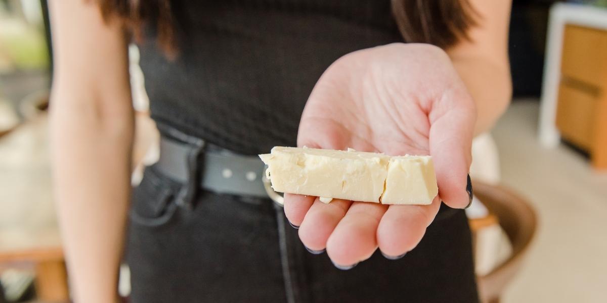 Woman in black outfit holding small block of cheddar cheese