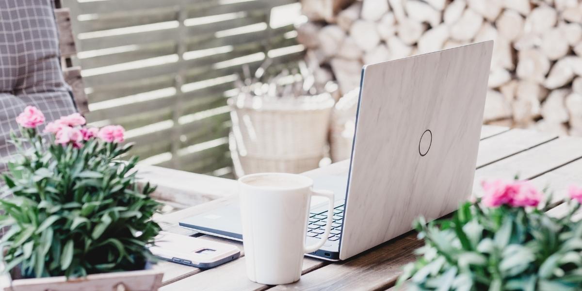 Laptop and coffee mug on outside wooden table