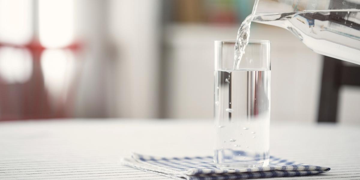 A glass of water being poured from a jug.