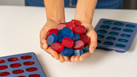 Hands Holding Cherry and Blue Raspberry Gummies