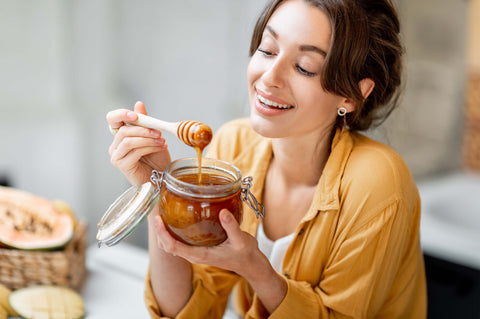 Woman Dipping Stick into Herb Infused Honey