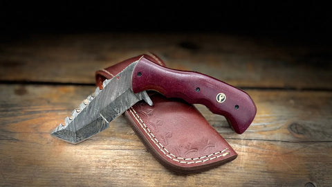 A Bighorn Steel foldable Damascus steel tracker knife with a maroon-coloured Micarta handle