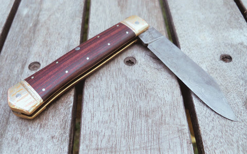 A folding Damascus steel knife with a wooden handle