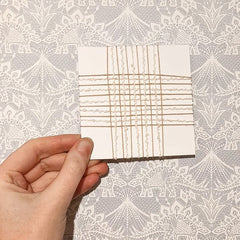 4 inch card woven with cream textured and ivory yarn in a loose square weave.