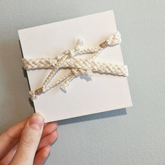 4inch card wrapped in cream yarn in an intricate braid.