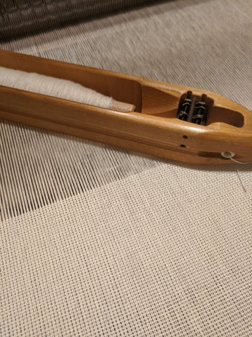 A close up of fabric being woven with shuttle