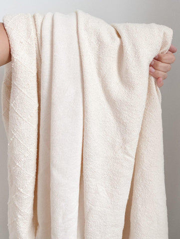 three organic cotton fabrics draped over an arm to show their light and texture