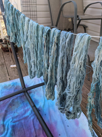 a clothes line draped with skeins of yarn in varying shades of blue.