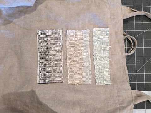 A close up of the same beige canvas tote bag. You can see that the patches have been attached with a simple machine stitch, and the edges have been left raw to fray adding texture and interest.