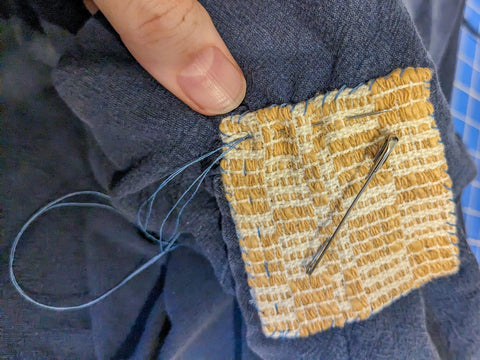 A final photo shows the patch with all four sides stiched down, the safety pins removed, and the needle stitching a straight line on the interior of the patch.