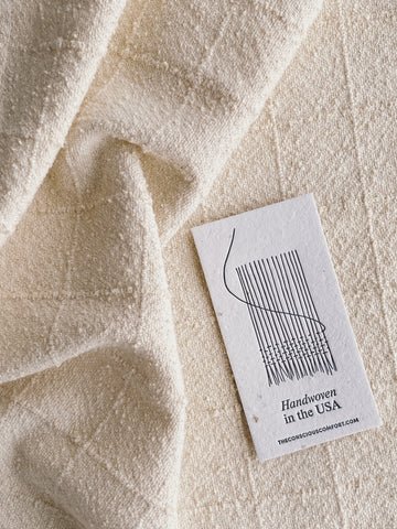 A printed card reading "handwoven in the USA" lays on top of creamy highly textured fabric. Photo supplied by Veronica Velez.