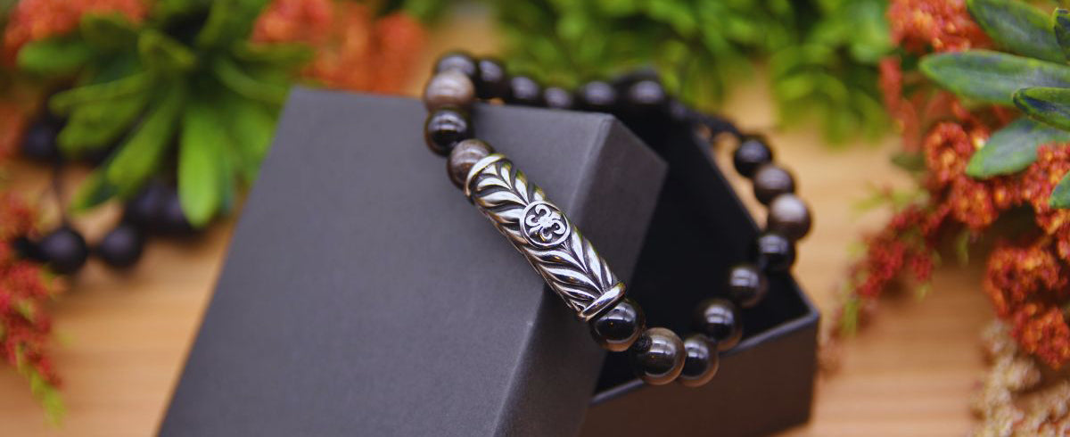 Image show men's bracelet with obsidian gemstones and stainless steel pendant by Emerald Sun Creations