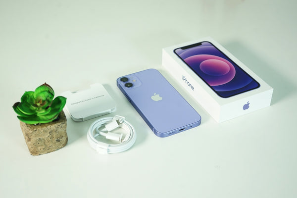 A purple iPhone and box on a white table