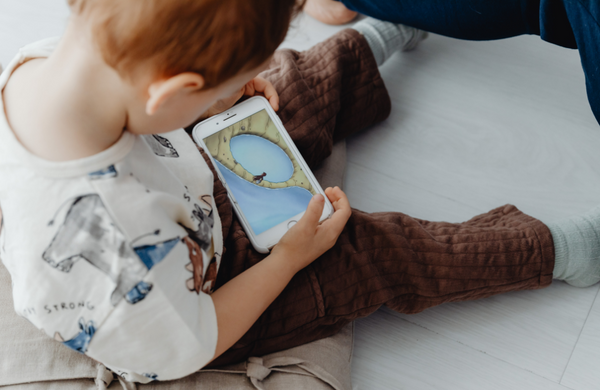 A young child looking down at a phone playing a video.