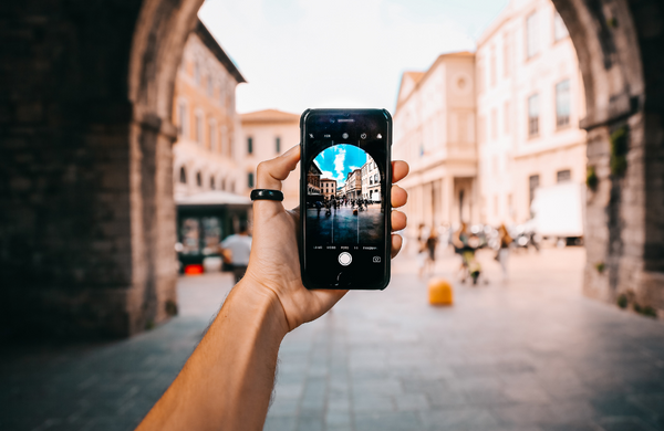 A hand holding a phone out taking a picture of a European street