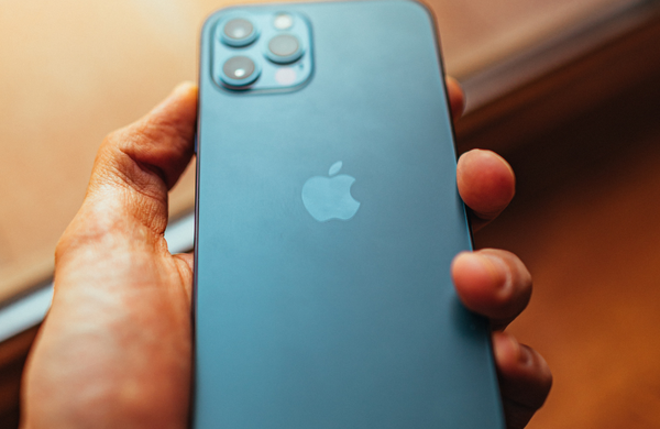 A hand holding a blue iPhone 15 with the screen facing towards their palm.