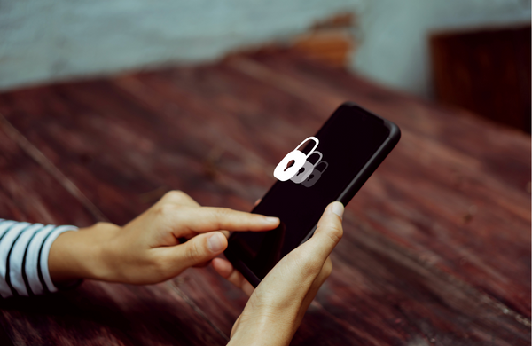 A person holding a black phone in one hand and pressing their finger to the screen with the other hand. There is a lock symbol coming up out of the screen. 