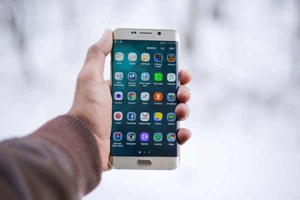 A hand holding a Samsung Galaxy S6 with the curved edge display.