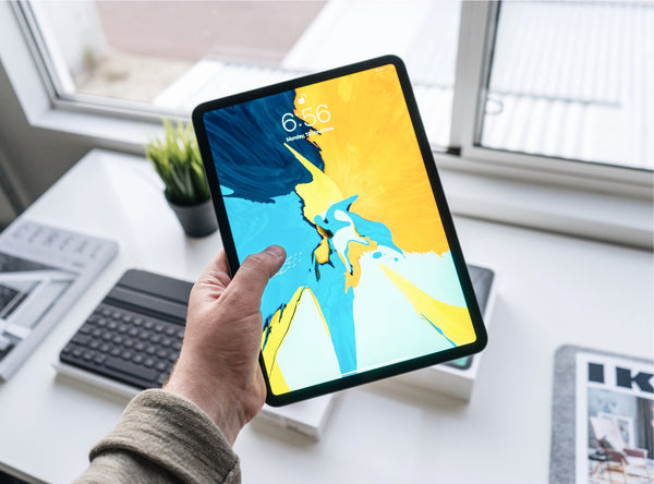 Man holding iPad with blue and yellow screensaver