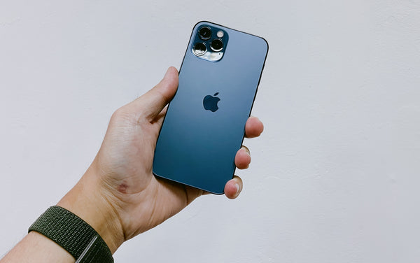 Close up of a man's hand holding a dark blue iPhone 13