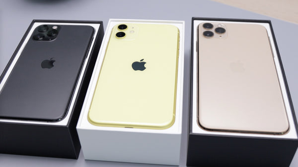 A black, a yellow and a rose gold iPhone in opened boxes in a line