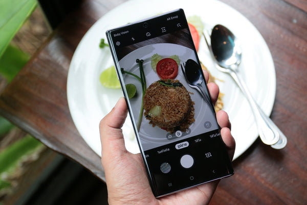 Person holding Samsung phone over food with camera open to see the food