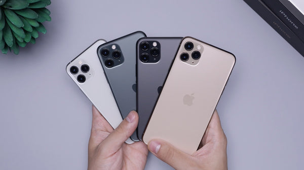Caucasian hands holding four different iPhones in a fan position 