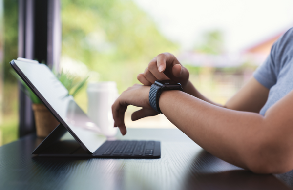 A man sitting at a desk pressing his smartwatch