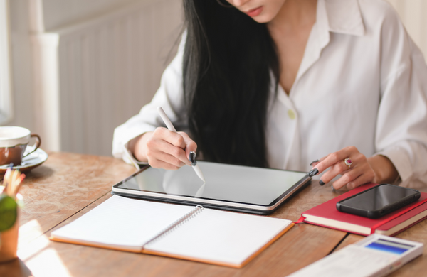 A woman sitting at a desk drawing on a tablet.