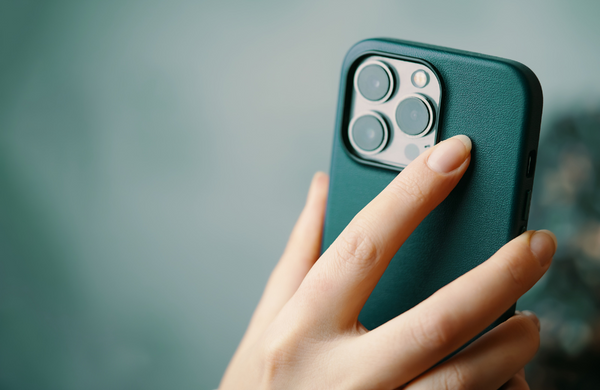A hand holding an iPhone in a green case with a matching green background.