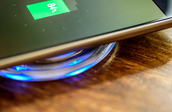 A phone wirelessly charging with 84% battery shown on the screen.