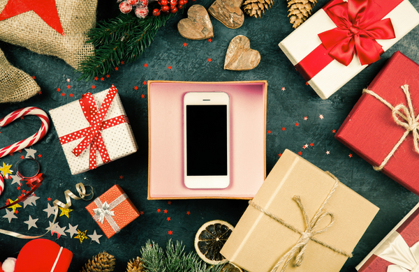 A smartphone in a gift box surrounded by Christmas decoration.
