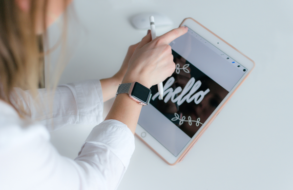 A woman using a tablet for design with 'hello' across the display.