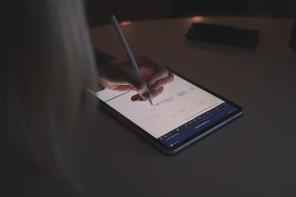 A person leaning over a tablet using the pen accessory to do design work.