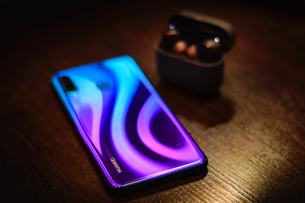 A metallic blue and purple Huawei phone face down on a wooden table