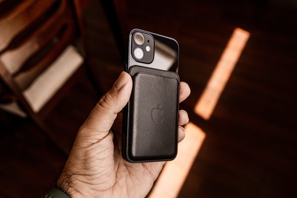 A hand holding a black iPhone 12 mini in a black leather case