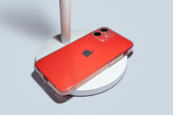 A red iPhone 12 mini face down on a white lamp base