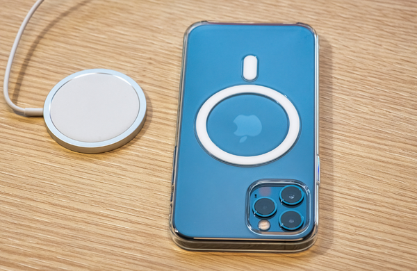 A blue iPhone with the MagSafe charging case next to a wireless charger.