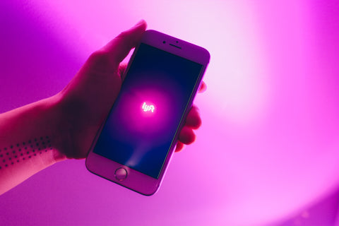 A white iPhone with a pink background