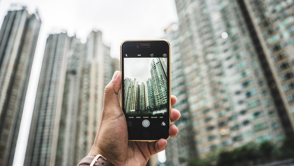 A smartphone with the camera open held up facing tall buildings