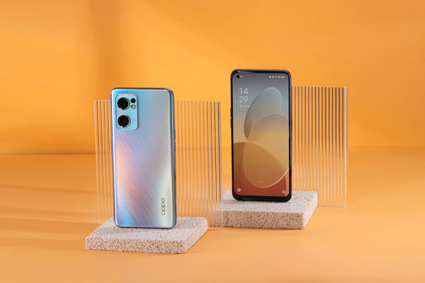 Two Oppo phones on makeshift display holders with an orange background