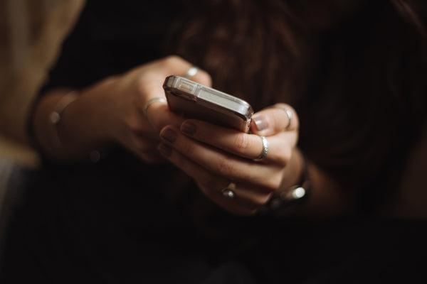 A woman cupping a silver smartphone in her hands.